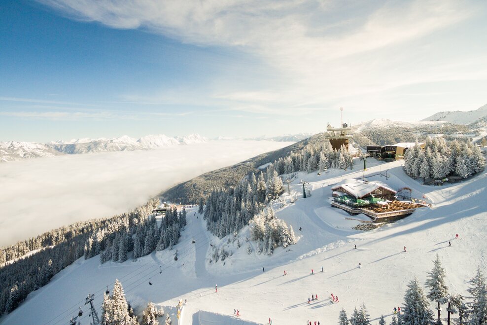Die Schafalm in einer Winterlandschaft umgeben von Skifahrern, Schnee und Bäumen | © Dominik Steiner