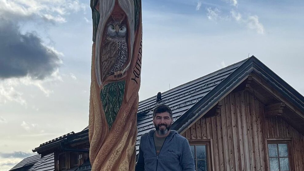 Ein Mann, der neben seiner selbst geschnitzten Holzskulptur steht | © Gemeinde Michaelaberg-Pruggern 